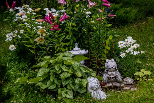 green garden with flowers and plaster figurine natural background photo