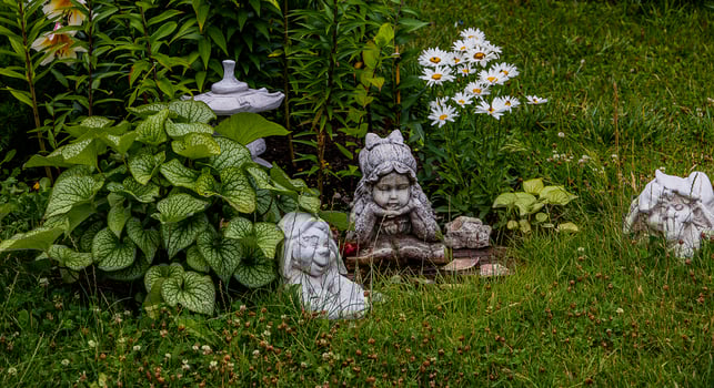 green garden with flowers and plaster figurine natural background photo