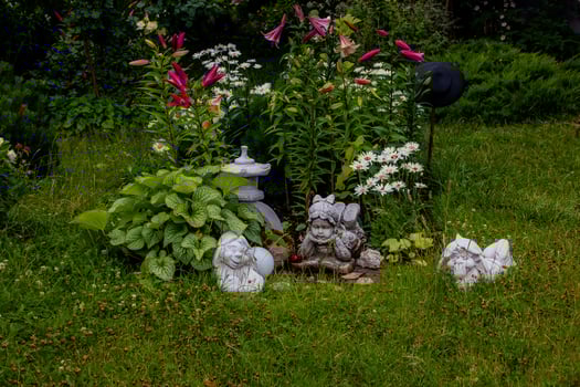 green garden with flowers and plaster figurine natural background photo