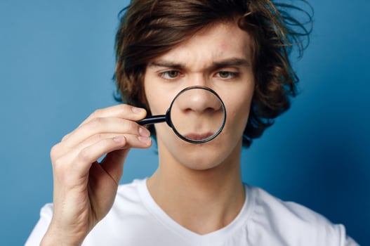 guy in a white t-shirt magnifying glass in his hands face problems photo