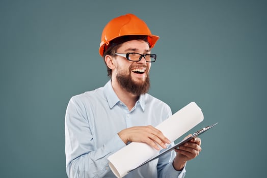 man in orange hard hat blueprints in hands construction industry blue background photo
