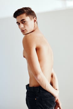 Sexy man in dark trousers on a light background naked torso photo