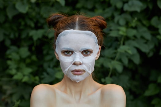 Nice woman face mask Front view clean skin cosmetology bushes in the background photo