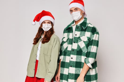Man and woman stand next to medical masks New Years Eve Christmas holiday studio photo