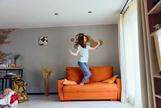 pretty woman in jeans is standing on the couch fun photo