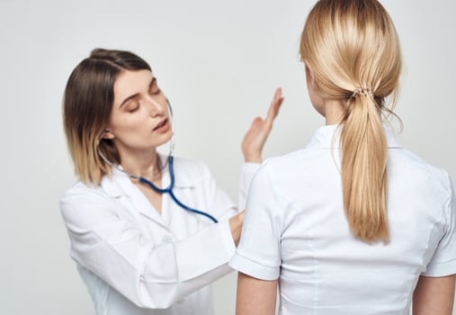 doctor woman in a medical gown with a stethoscope communicates with a patient back view photo