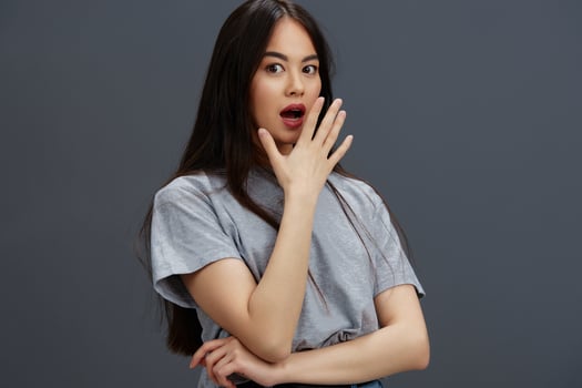 portrait woman with long hair in a gray T-shirt gesturing with hands Gray background photo