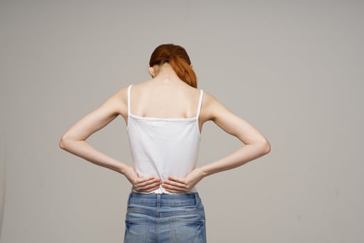 woman in white t-shirt back pain health problems osteoporosis studio treatment photo