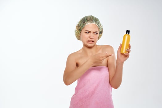 woman with unhappy facial expression in pink towel lotion skin care photo