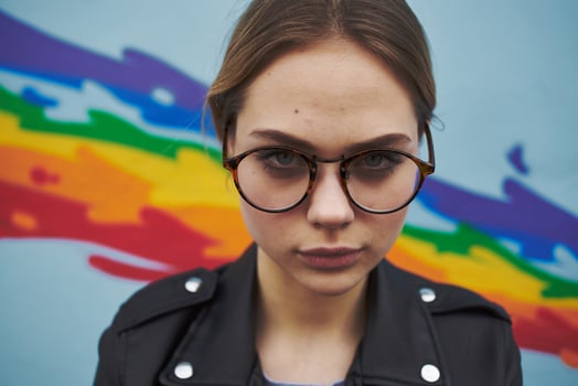 the artist with glasses near the multi-colored graffiti on the wall photo