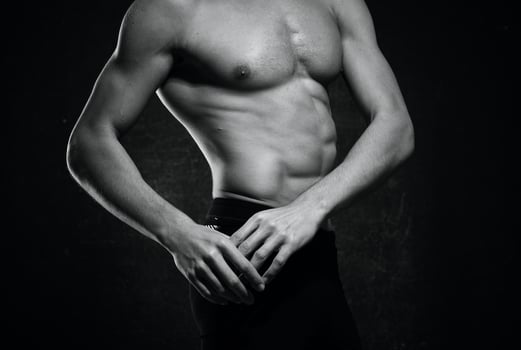sporty man naked torso inflated body posing dark background photo