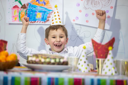 Happy birthday child. The boy at the festive table with a cap. photo