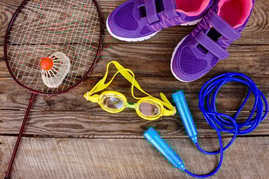 Sports equipment the birdie is on the racket, skipping rope, swimming goggles and sneakers on wooden background photo