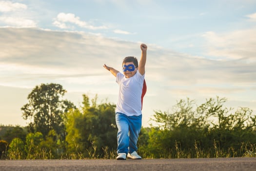 Portrait of adorable kid boy having fun outdoor. Little child play superhero photo