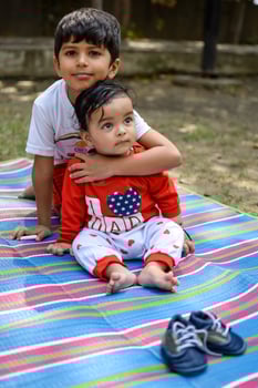 Two happy boys in society park, happy Asian brothers who are smiling happily together. Brothers play outdoors in summer, best friends. Toddler baby boy playing with his happy brother in the garden photo