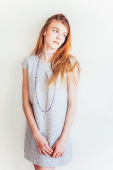 Beauty teenage girl. Portrait young teen woman in grey dress against white wall background. European woman. photo