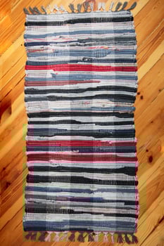 Rustic wicker rug on a wooden floor. Multi-colored Slavic carpet. photo
