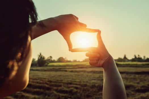 woman hand framing view distant over sunset. business concept photo