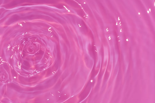 Defocus blurred transparent purple colored clear calm water surface texture with splash, bubble. Shining purple water ripple background. Surface of water in swimming pool. Pink bubble water shine. photo