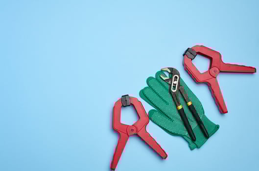 Green glove and metal universal adjustable wrench on a blue background, top view photo