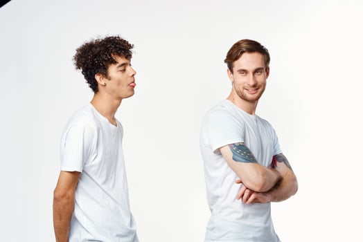 Two cheerful friends in white t-shirts stand side by side cropped view photo