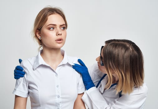 A nurse in blue gloves examines a patient in a white T-shirt on a light background photo