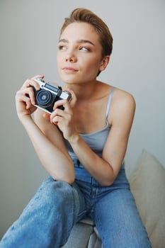 Woman photographer shooting in studio on old film camera at home on couch portrait, white background, free copy space, freelance photographer photo