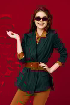 cheerful woman in suit sunglasses smile cropped view red background studio photo