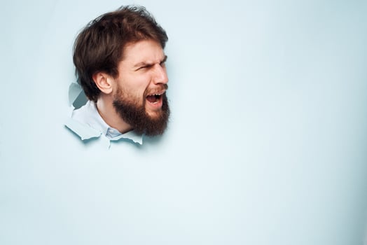 A disgruntled man head peeps out from behind the wall of an office career lifestyle photo