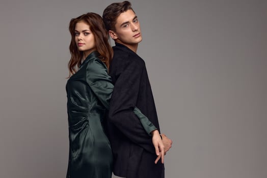 A sexy woman in a dress and a man in a suit stand with their backs to each other on a gray background photo