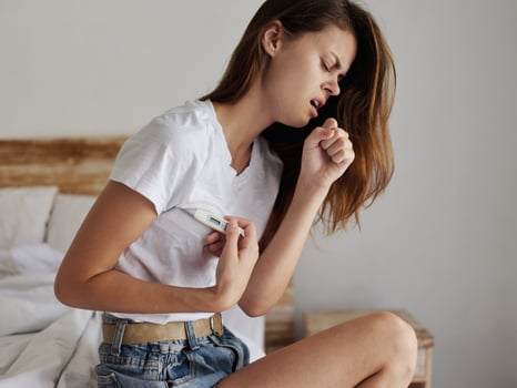 woman with cold armpit thermometer checks temperature photo