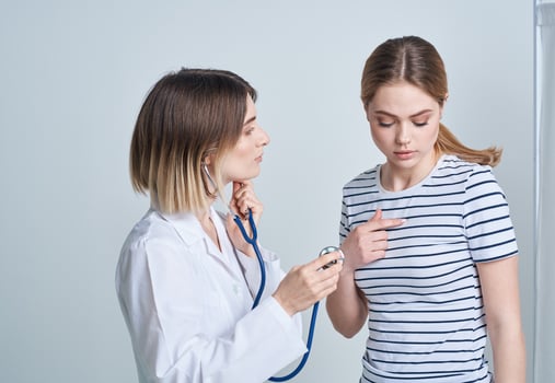 doctor woman in medical gown with stethoscope listens to patient's heart photo