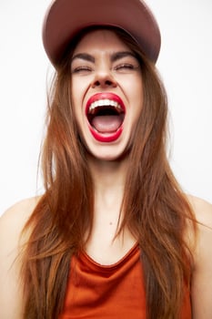 Portrait of a woman in a cap Fun mouth wide open closed eyes red lips photo