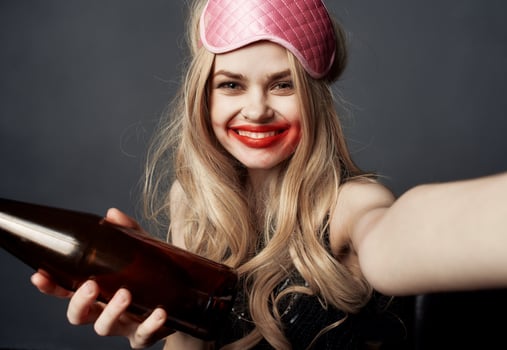 Drunk blonde girl with a bottle of beer gestures with her hands and a bright makeup addiction model photo