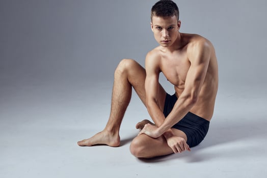 male athlete sitting on floor with pumped up body posing photo