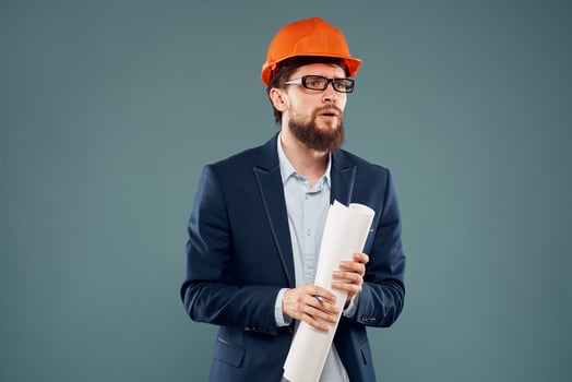 A man in orange paint blueprints in the hands of a construction industry official photo