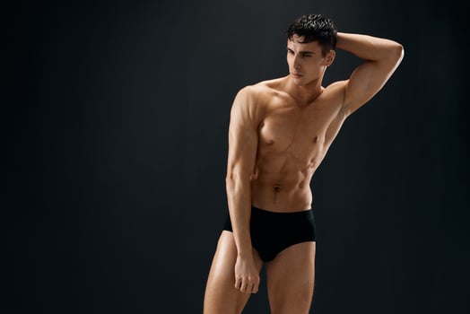 sporty man with pumped up abs posing in dark studio panties photo
