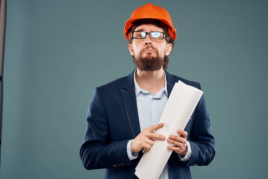 Male engineer professional orange hard hat safety construction blueprints in hands photo