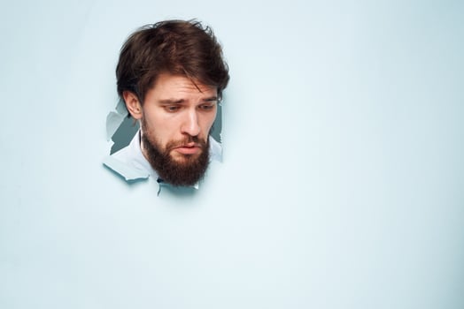 A disgruntled man head peeps out from behind the wall of an office career lifestyle photo
