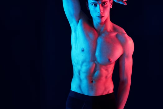 male athlete with neon skin color on isolated background holds hand behind head cropped view photo