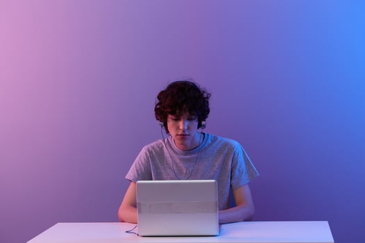 guy in headphones in front of laptop entertainment violet background photo