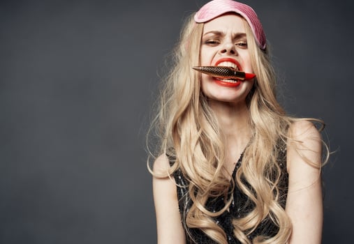 Drunk woman with lipstick in hand and pink mask on her face photo
