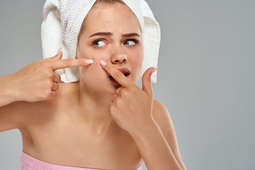 pretty woman with towel on her head squeezes out pimples on her face photo