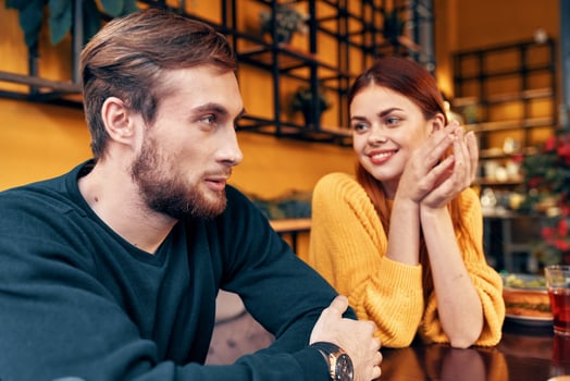 man and woman are sitting in a cafe at the table and gesturing with their hands friends emotions fun interior photo