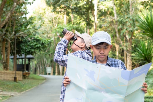 Asian boys using binoculars to do the birdwatching in tropical forest during summer camp, idea for learning creatures, wildlife animals and insects outside the classroom. photo