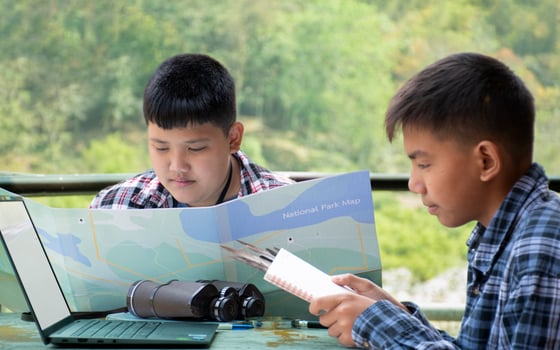Asian boys using binoculars to do the birdwatching in tropical forest during summer camp, idea for learning creatures, wildlife animals and insects outside the classroom. photo