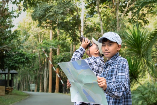 Asian boys using binoculars to do the birdwatching in tropical forest during summer camp, idea for learning creatures, wildlife animals and insects outside the classroom. photo