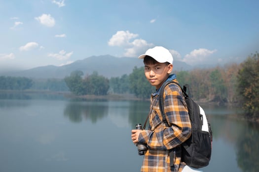 Asian boys using binoculars to do the birdwatching in tropical forest during summer camp, idea for learning creatures, wildlife animals and insects outside the classroom. photo