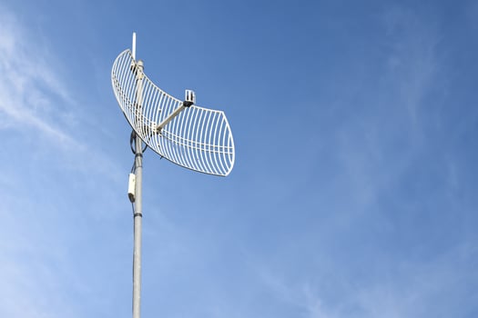 Internet wireless wifi receiver and repeater installed on metal pole on the roof of the building to service internet to users in local village, soft and selective focus. photo