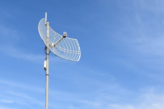 Internet wireless wifi receiver and repeater installed on metal pole on the roof of the building to service internet to users in local village, soft and selective focus. photo